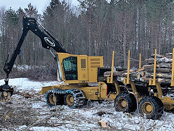 machine placing cut logs down for transport