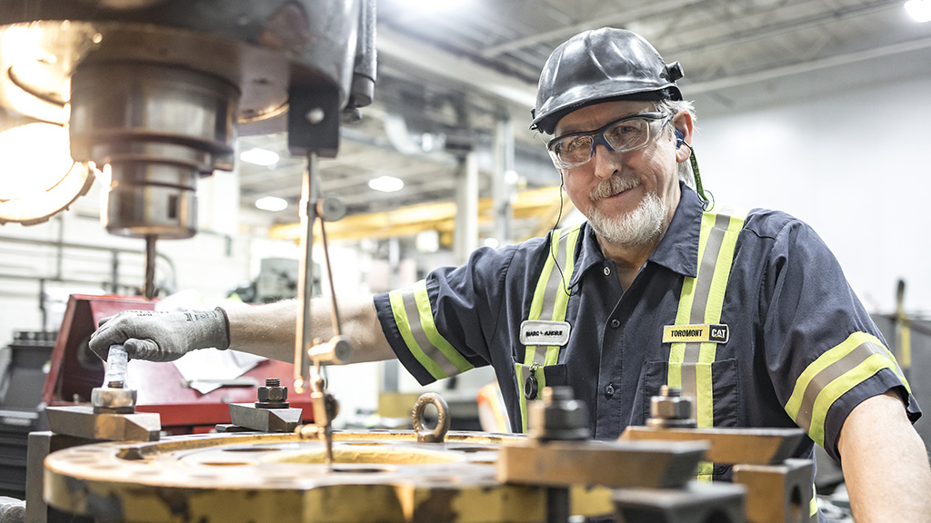Construction worker smiling in front of a machine in warehouse