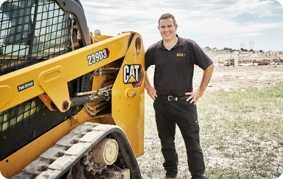 Cat worker smiling next to a bulldozer